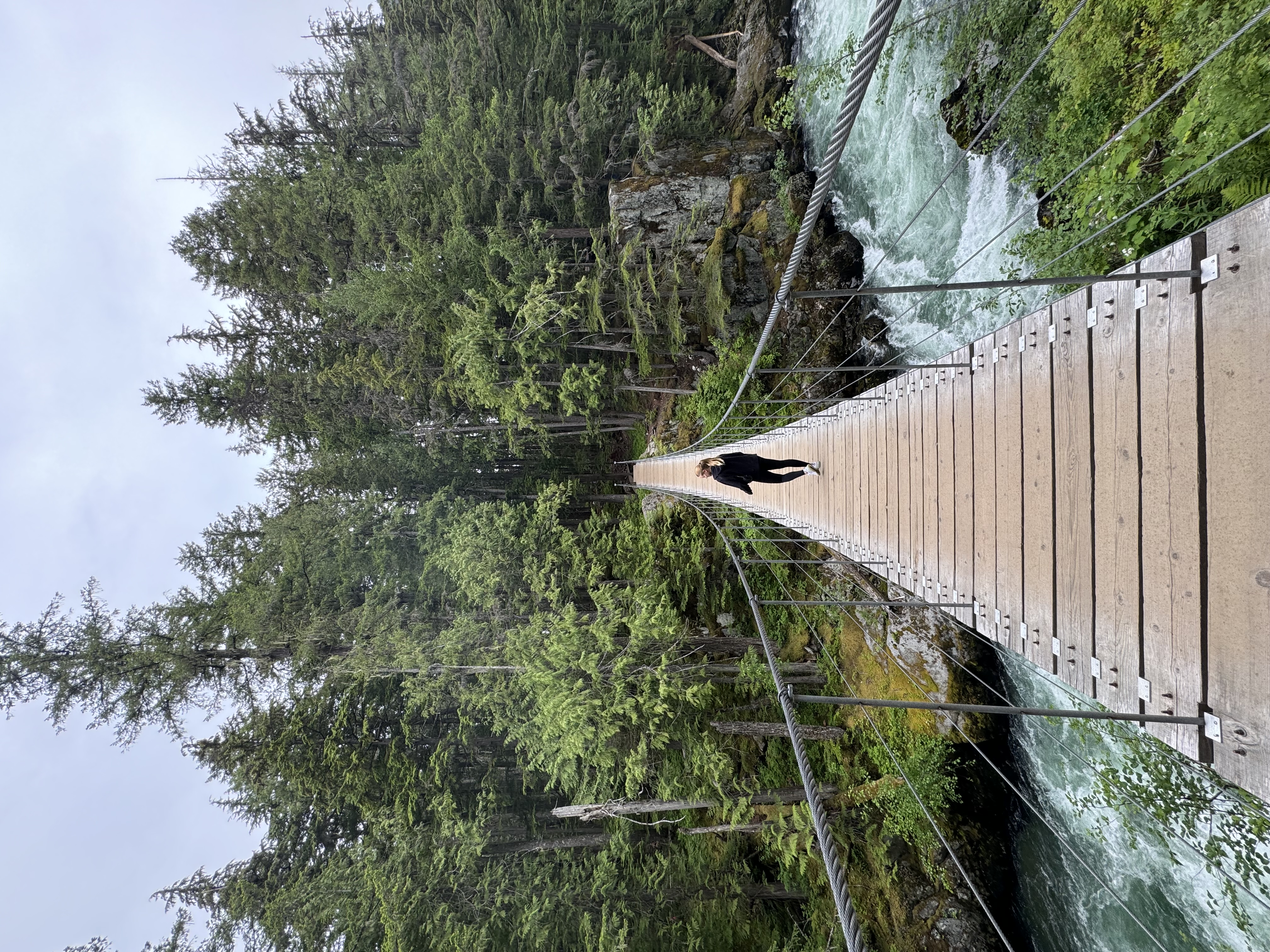 Lena standing on a bridge in a tree-lined setting